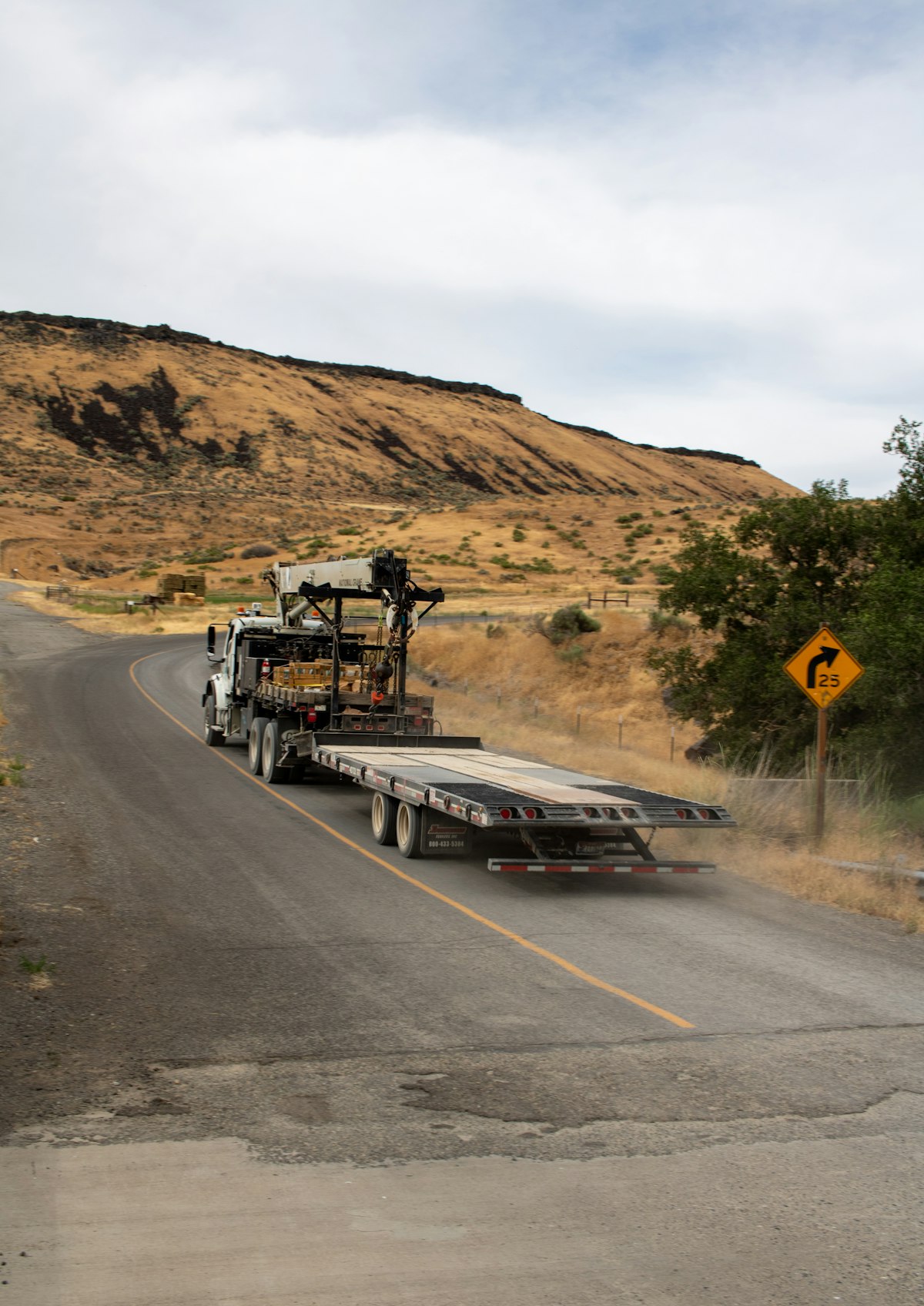 A flatbed rig taking a bend on a rural road